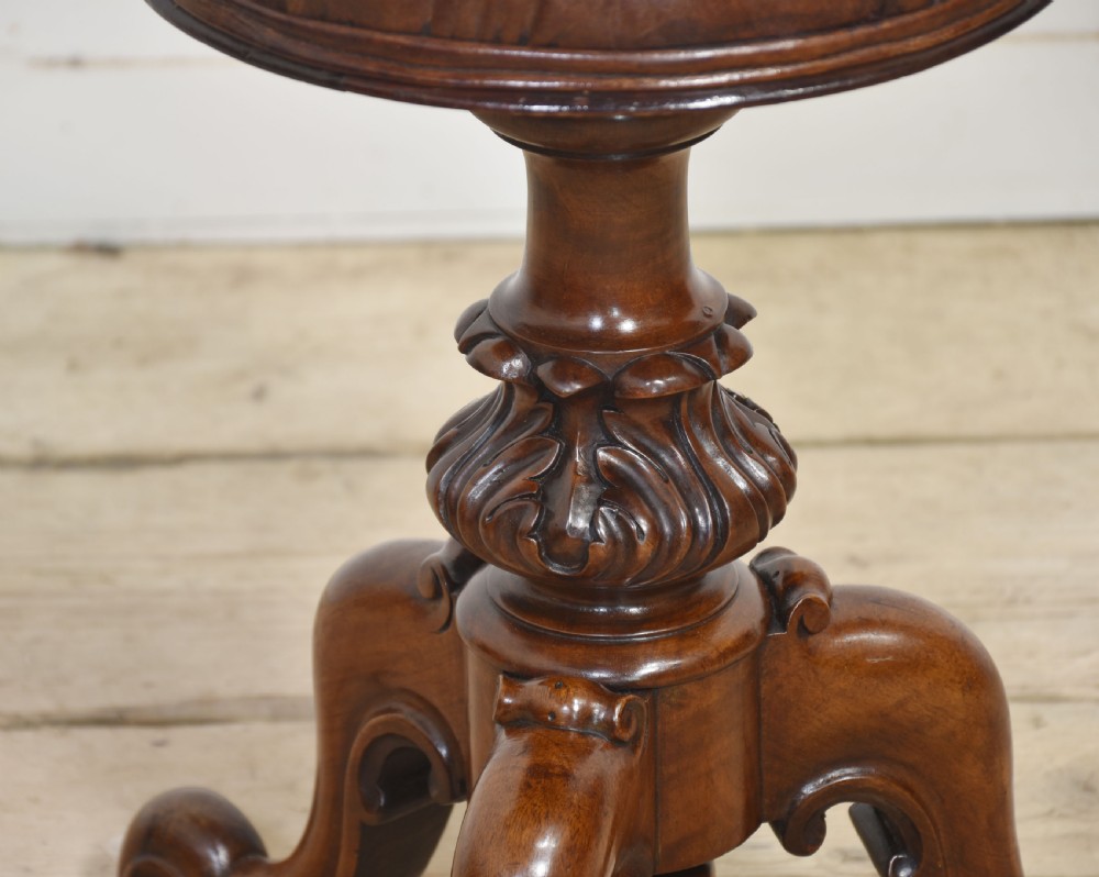 A Victorian walnut adjustable piano stool featuring a buttoned brown leather circular seat, carved central baluster column, and tripod scrolled legs. View V