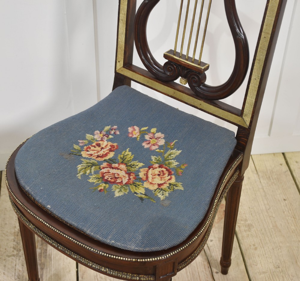 A pair of antique mahogany side chairs featuring open lyre-shaped backrests with brass accents and blue fabric seats upholstered with floral tapestry. View III
