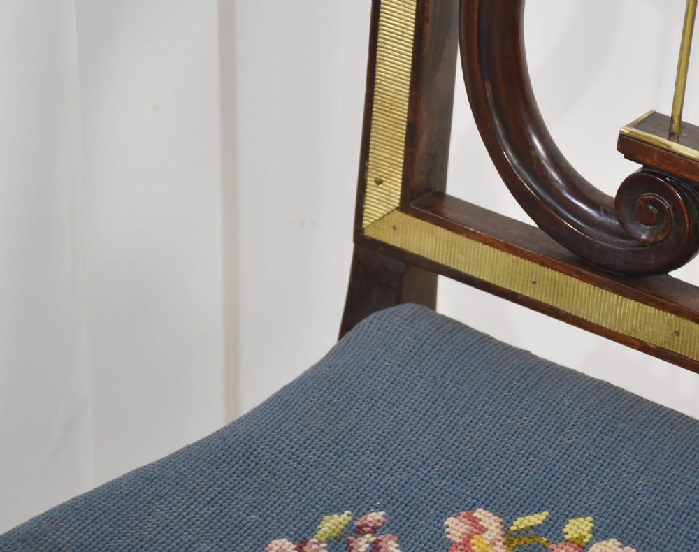 A pair of antique mahogany side chairs featuring open lyre-shaped backrests with brass accents and blue fabric seats upholstered with floral tapestry. View VI