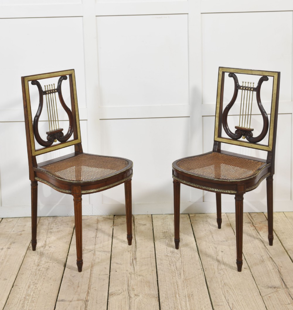 A pair of antique mahogany side chairs featuring open lyre-shaped backrests with brass accents and blue fabric seats upholstered with floral tapestry. View VIII