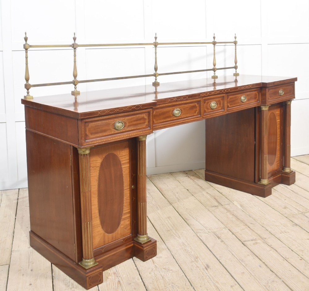A 19th-century mahogany pedestal sideboard with satinwood oval panel inlays, reeded columns, five upper drawers, and a top brass gallery rail. View IX