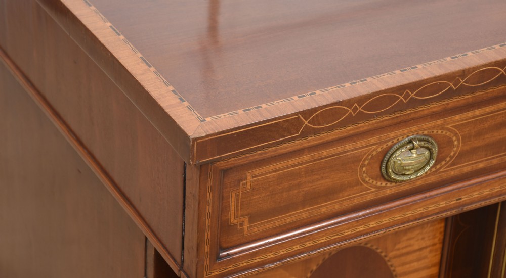 A 19th-century mahogany pedestal sideboard with satinwood oval panel inlays, reeded columns, five upper drawers, and a top brass gallery rail. View XI