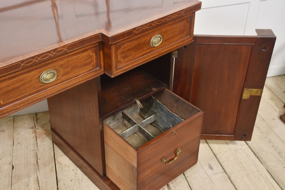 A 19th-century mahogany pedestal sideboard with satinwood oval panel inlays, reeded columns, five upper drawers, and a top brass gallery rail. View XII
