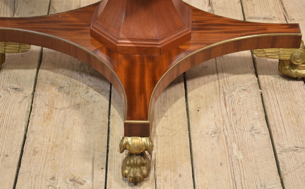 A circular mahogany coffee table featuring a polished flame mahogany veneer top, a thin brass gallery rim, and four curved legs ending in brass lion paw feet. View II
