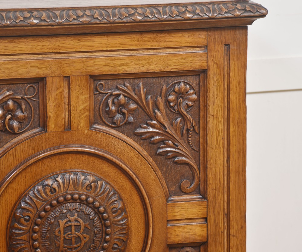 A 19th-century carved oak low cabinet featuring two door panels adorned with central carved roundels and foliate motifs. View III