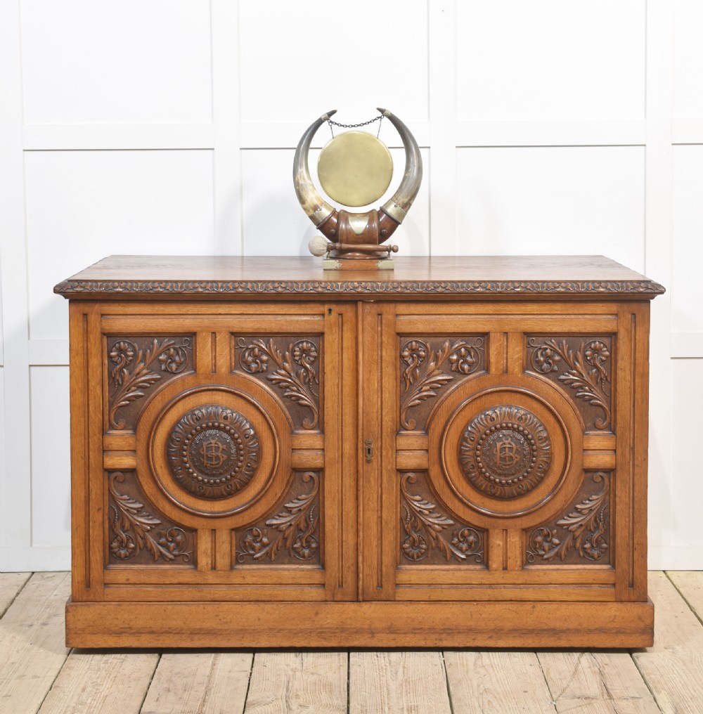 A 19th-century carved oak low cabinet featuring two door panels adorned with central carved roundels and foliate motifs. View VII