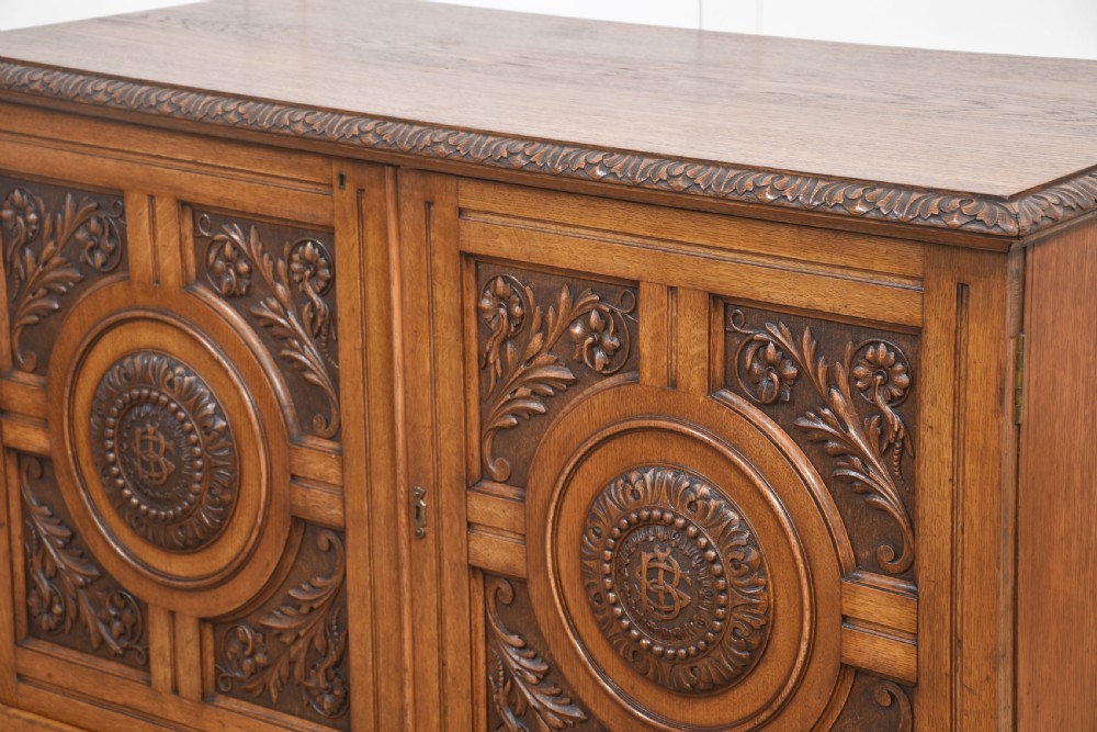 A 19th-century carved oak low cabinet featuring two door panels adorned with central carved roundels and foliate motifs. View XIV