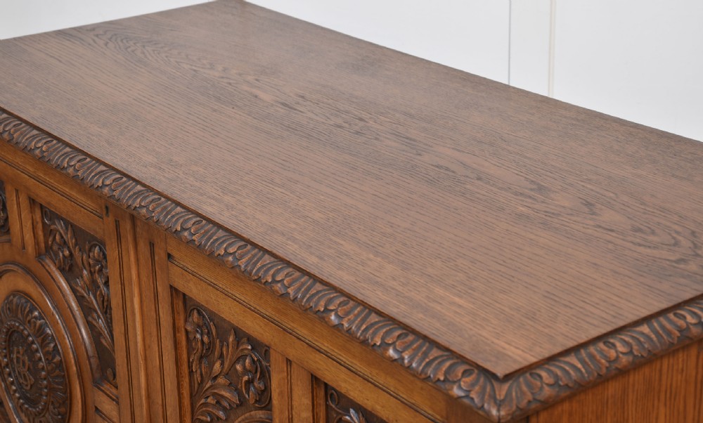 A 19th-century carved oak low cabinet featuring two door panels adorned with central carved roundels and foliate motifs. View XVII
