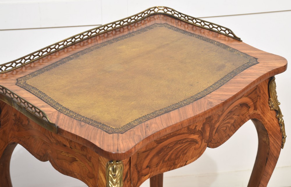 A French Louis XV style kingwood side table featuring a leather inset top with a pierced brass gallery, marquetry inlaid frieze, cabriole legs, and ornate gilt-metal mounts. View XII