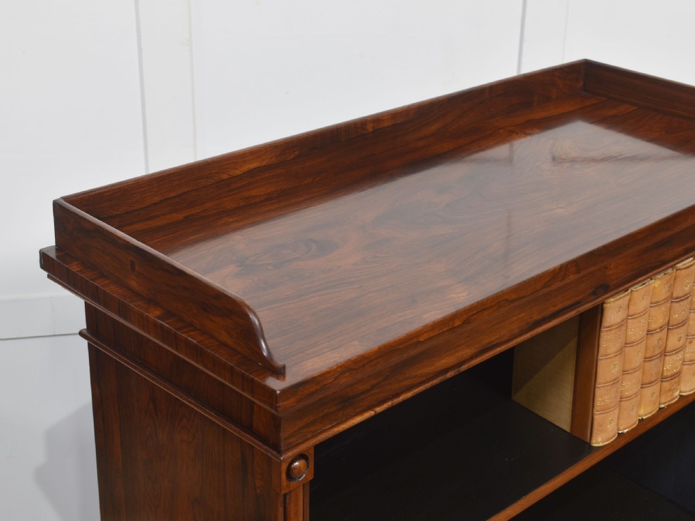 A 19th-century dark rosewood open bookcase featuring three tiers of shelving, a gallery top, corner roundels, and a solid plinth base. View V