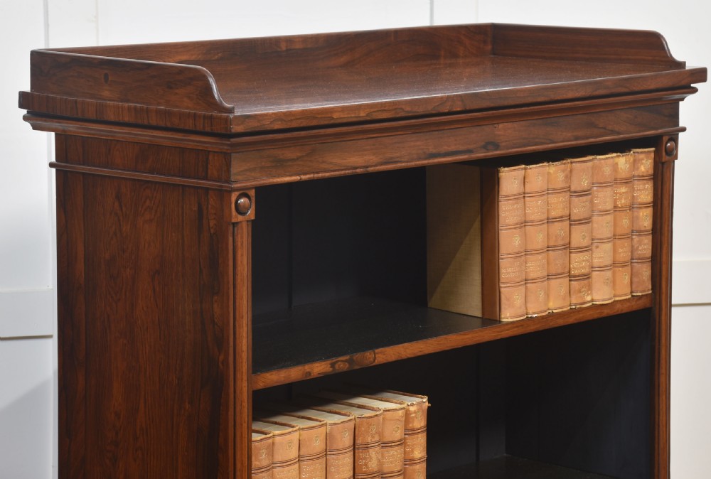 A 19th-century dark rosewood open bookcase featuring three tiers of shelving, a gallery top, corner roundels, and a solid plinth base. View VIII