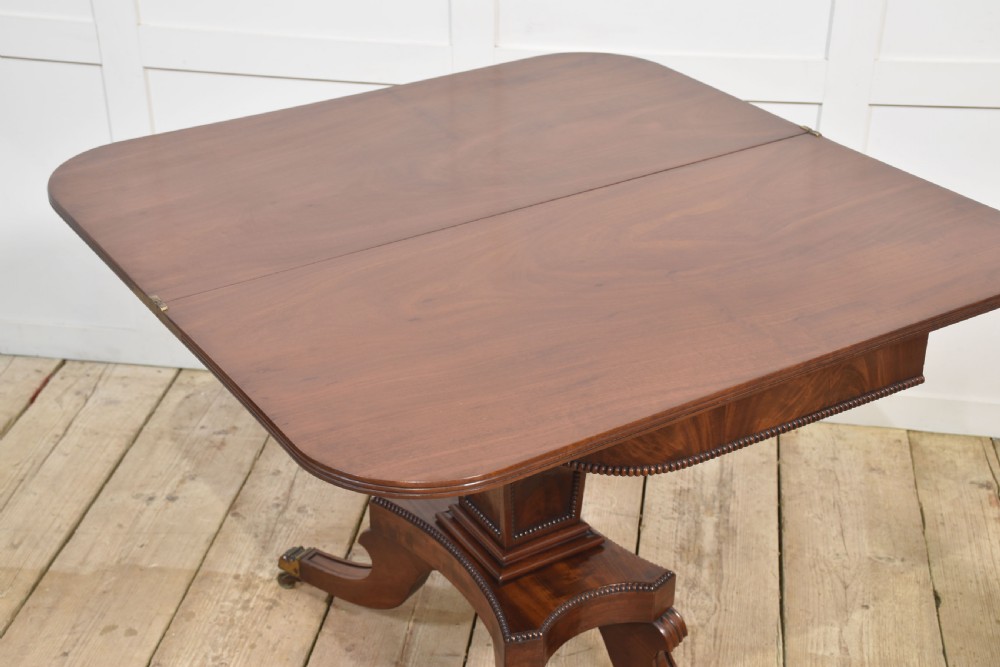 A Regency mahogany tea table featuring a fold-over top, central pedestal support, and four splayed legs with brass paw castors. View VII