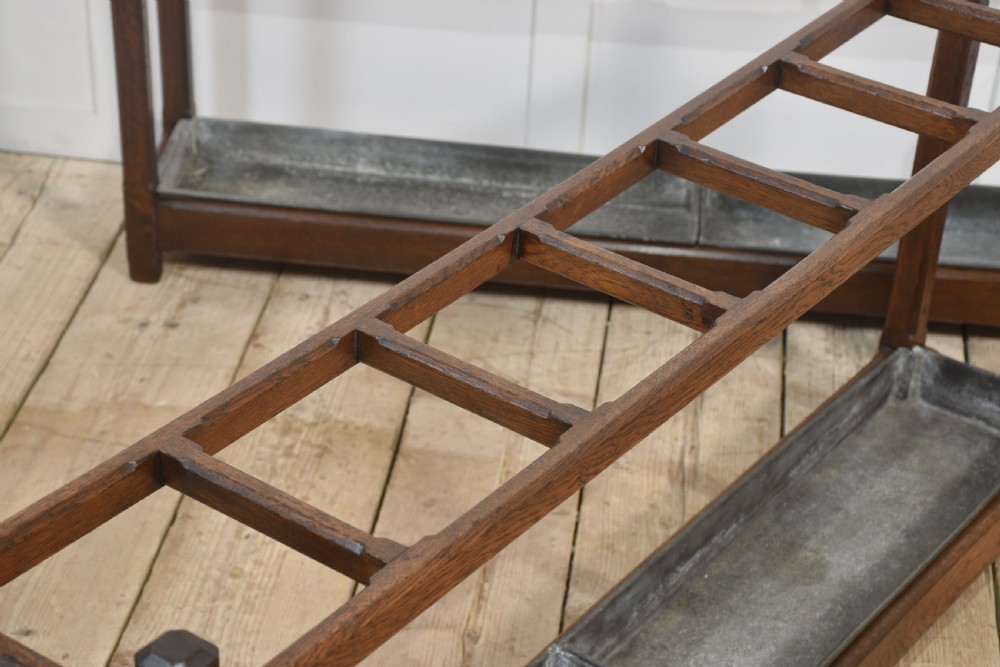 A pair of long dark oak Gothic Revival umbrella stands featuring divided top compartments and metal drip trays. View VI