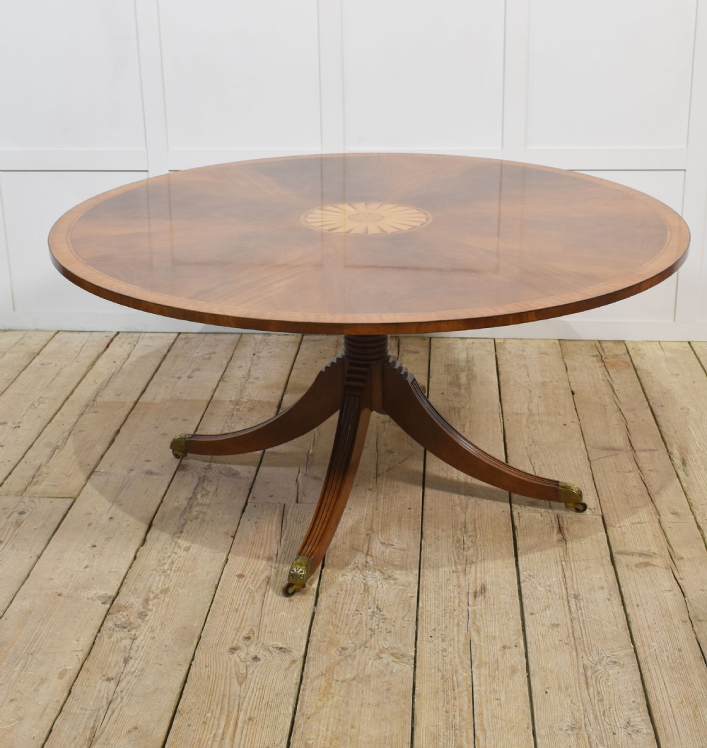 A circular mahogany dining table featuring crossbanded veneer edging, a central revolving lazy susan with marquetry inlay, and a pedestal support with four reeded legs terminating in brass castors. View II