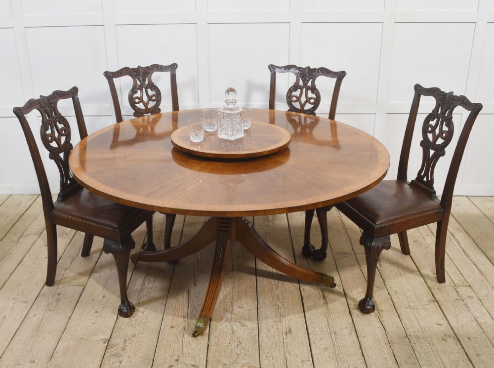 A circular mahogany dining table featuring crossbanded veneer edging, a central revolving lazy susan with marquetry inlay, and a pedestal support with four reeded legs terminating in brass castors. View IX