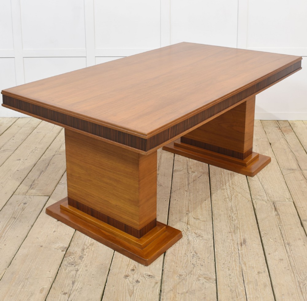 An Art Deco rectangular walnut dining table featuring twin block pedestal supports and dark crossbanded border details along the apron. View III