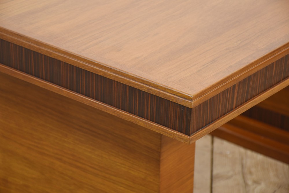 An Art Deco rectangular walnut dining table featuring twin block pedestal supports and dark crossbanded border details along the apron. View IX