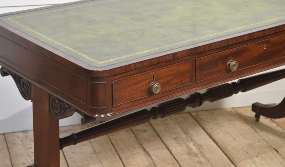 A Regency mahogany library table featuring a green leather inset top, brass knob drawers, a turned central stretcher, and reeded sabre legs on brass castors. View III