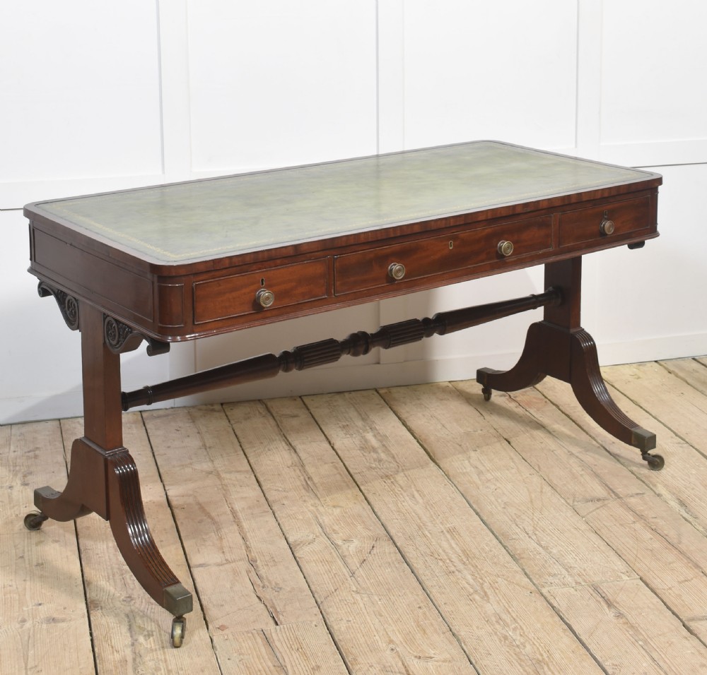 A Regency mahogany library table featuring a green leather inset top, brass knob drawers, a turned central stretcher, and reeded sabre legs on brass castors. View VIII