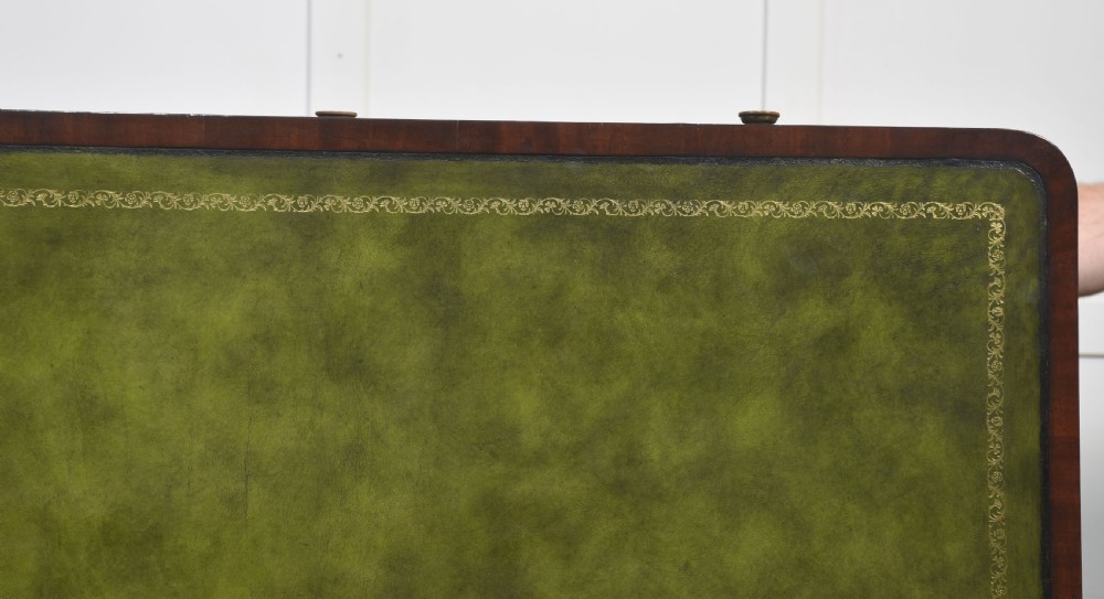 A Regency mahogany library table featuring a green leather inset top, brass knob drawers, a turned central stretcher, and reeded sabre legs on brass castors. View XVII