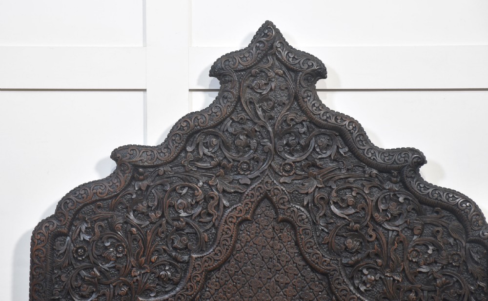A pair of 19th-century dark hardwood ceremonial armchairs featuring intricate relief carvings, arched backrests, and elephant motifs on the base panels. View VIII