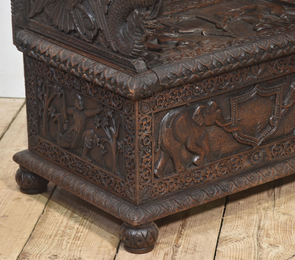 A pair of 19th-century dark hardwood ceremonial armchairs featuring intricate relief carvings, arched backrests, and elephant motifs on the base panels. View XI
