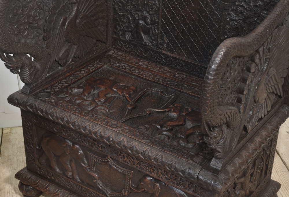 A pair of 19th-century dark hardwood ceremonial armchairs featuring intricate relief carvings, arched backrests, and elephant motifs on the base panels. View XIV