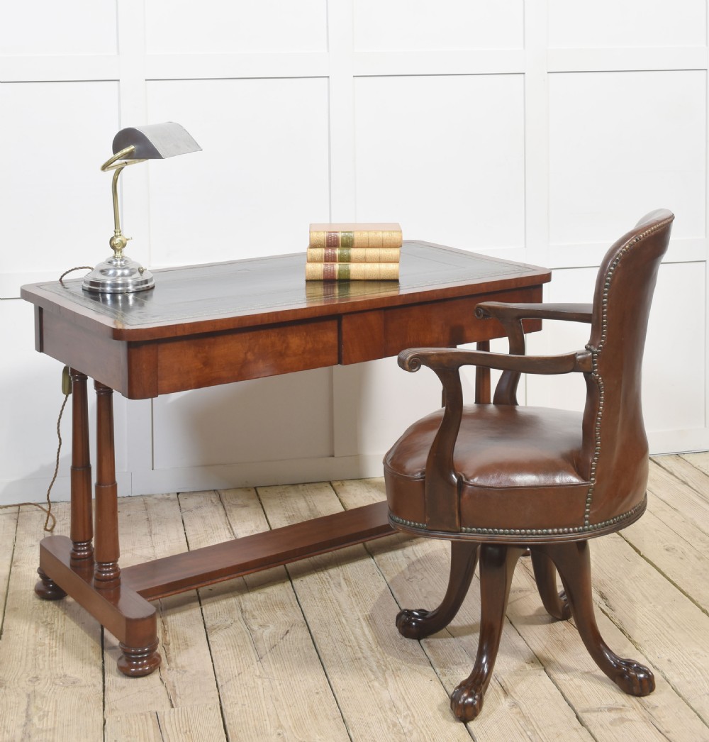 A mahogany writing table with a green leather inset top, two frieze drawers, turned trestle legs, and a stretcher base. View II