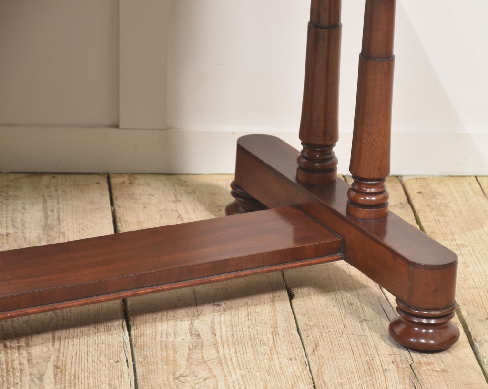 A mahogany writing table with a green leather inset top, two frieze drawers, turned trestle legs, and a stretcher base. View III