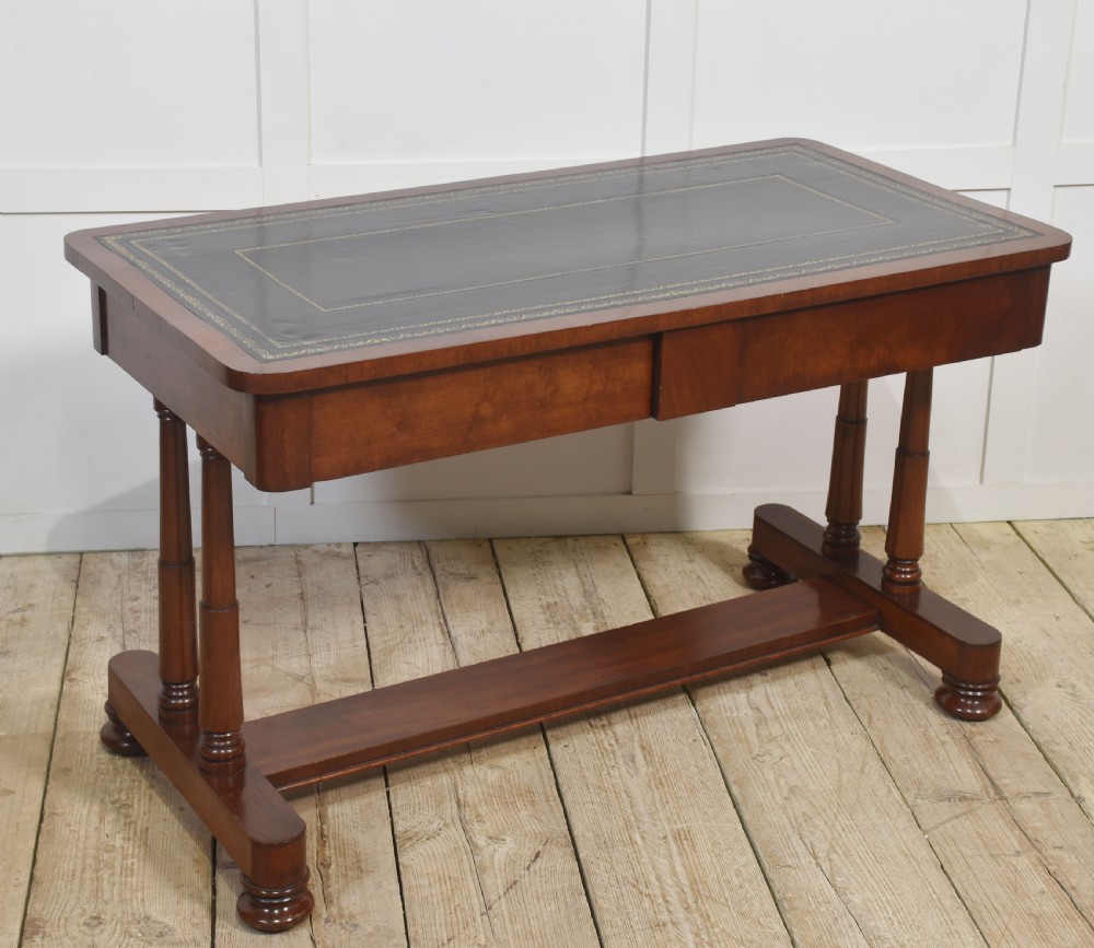 A mahogany writing table with a green leather inset top, two frieze drawers, turned trestle legs, and a stretcher base. View V