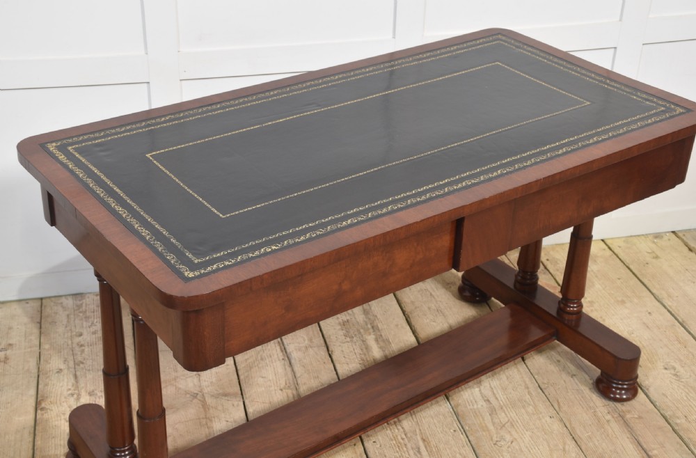 A mahogany writing table with a green leather inset top, two frieze drawers, turned trestle legs, and a stretcher base. View VIII