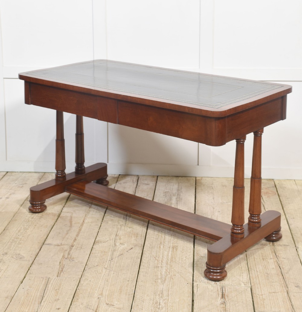 A mahogany writing table with a green leather inset top, two frieze drawers, turned trestle legs, and a stretcher base. View X