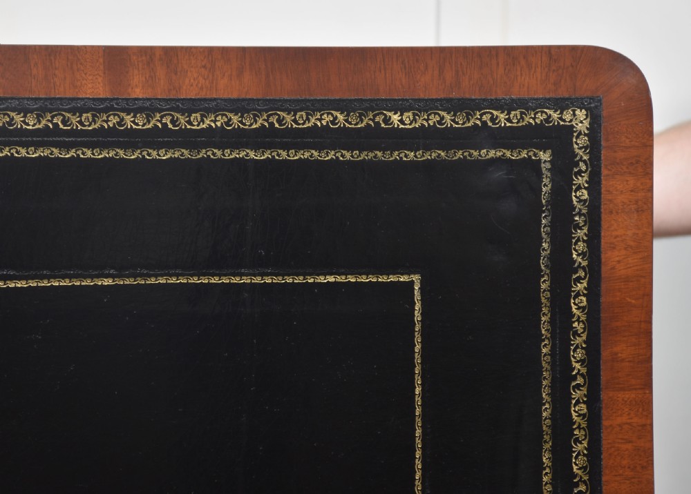 A mahogany writing table with a green leather inset top, two frieze drawers, turned trestle legs, and a stretcher base. View XV
