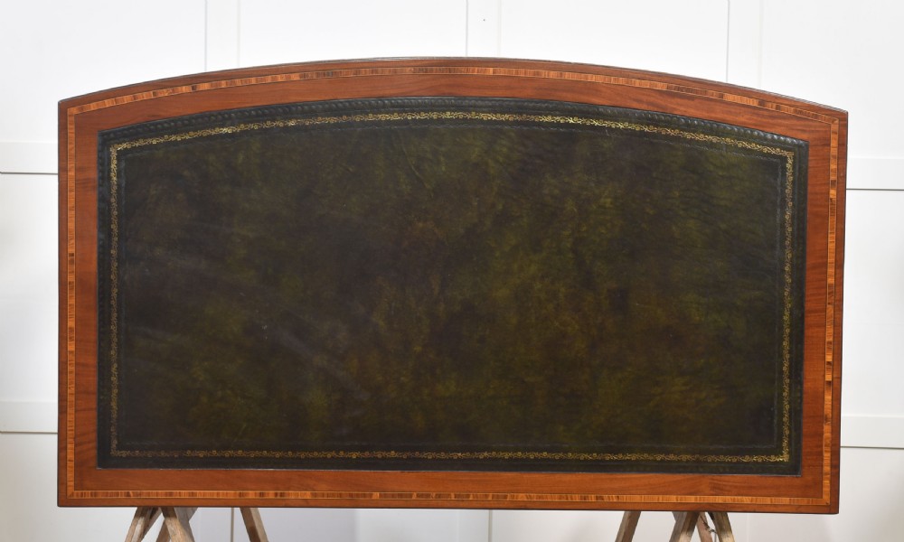 An antique mahogany writing desk featuring a leather insert top, boxwood stringing inlay, seven drawers with brass handles, and tapered legs on castors. View XIV