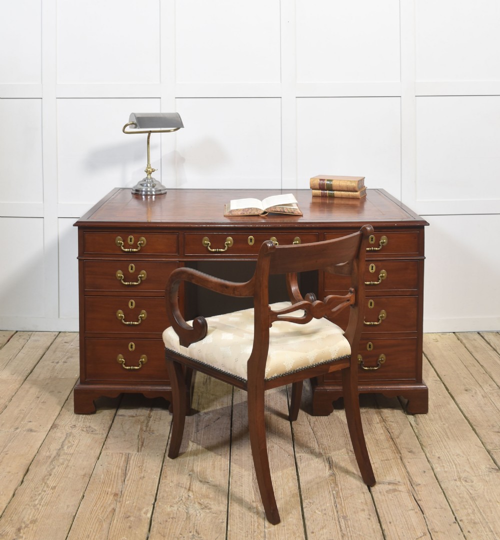 An antique mahogany partners desk featuring a leather-inset writing surface, brass swan-neck handles, twin pedestals, and ogee bracket feet. View II