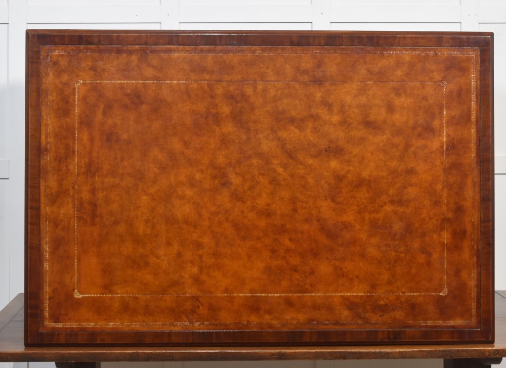 An antique mahogany partners desk featuring a leather-inset writing surface, brass swan-neck handles, twin pedestals, and ogee bracket feet. View XV