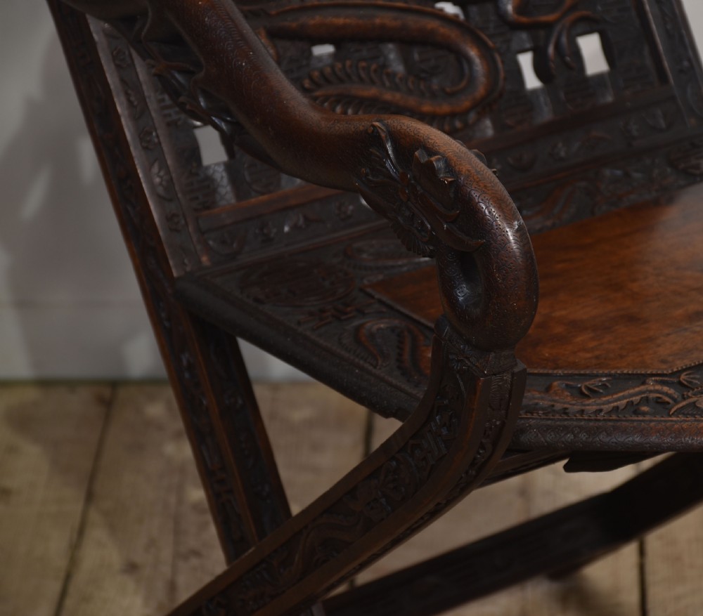 A pair of 19th-century Chinese folding hardwood armchairs featuring intricate dragon carvings on the backrests and serpentine arms supported by X-frame legs. View VI
