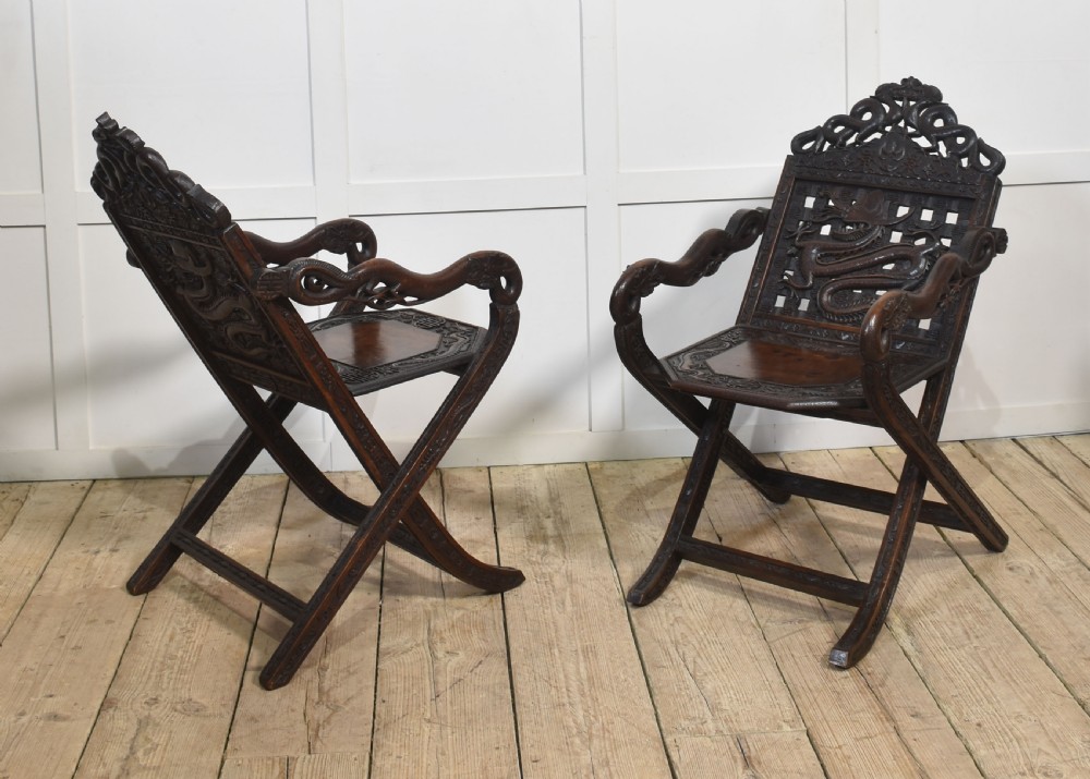 A pair of 19th-century Chinese folding hardwood armchairs featuring intricate dragon carvings on the backrests and serpentine arms supported by X-frame legs. View IX
