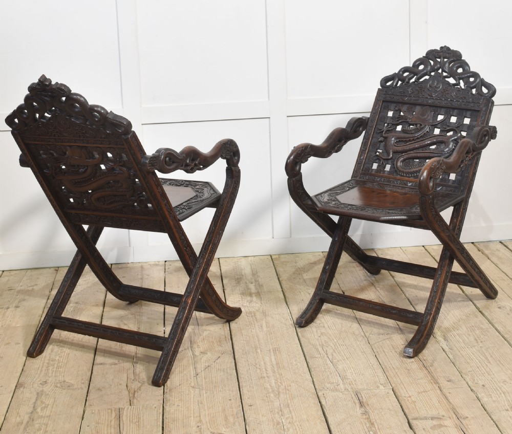 A pair of 19th-century Chinese folding hardwood armchairs featuring intricate dragon carvings on the backrests and serpentine arms supported by X-frame legs. View XI
