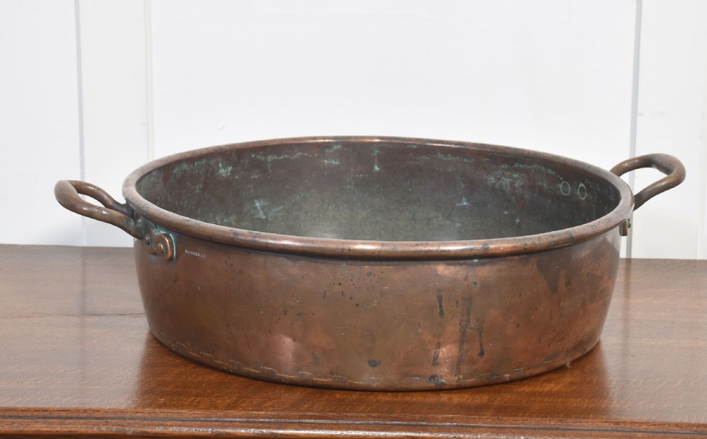 A large, wide, round 19th-century copper preserve pan featuring a rolled rim and two riveted loop handles.