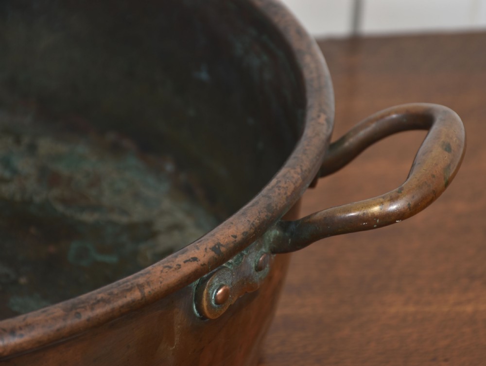 A large, wide, round 19th-century copper preserve pan featuring a rolled rim and two riveted loop handles. View IV