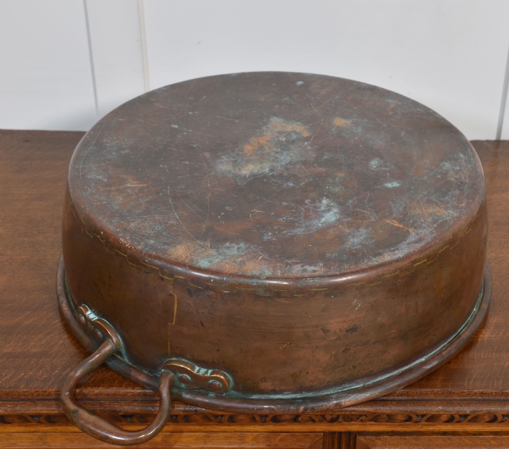 A large, wide, round 19th-century copper preserve pan featuring a rolled rim and two riveted loop handles. View VIII