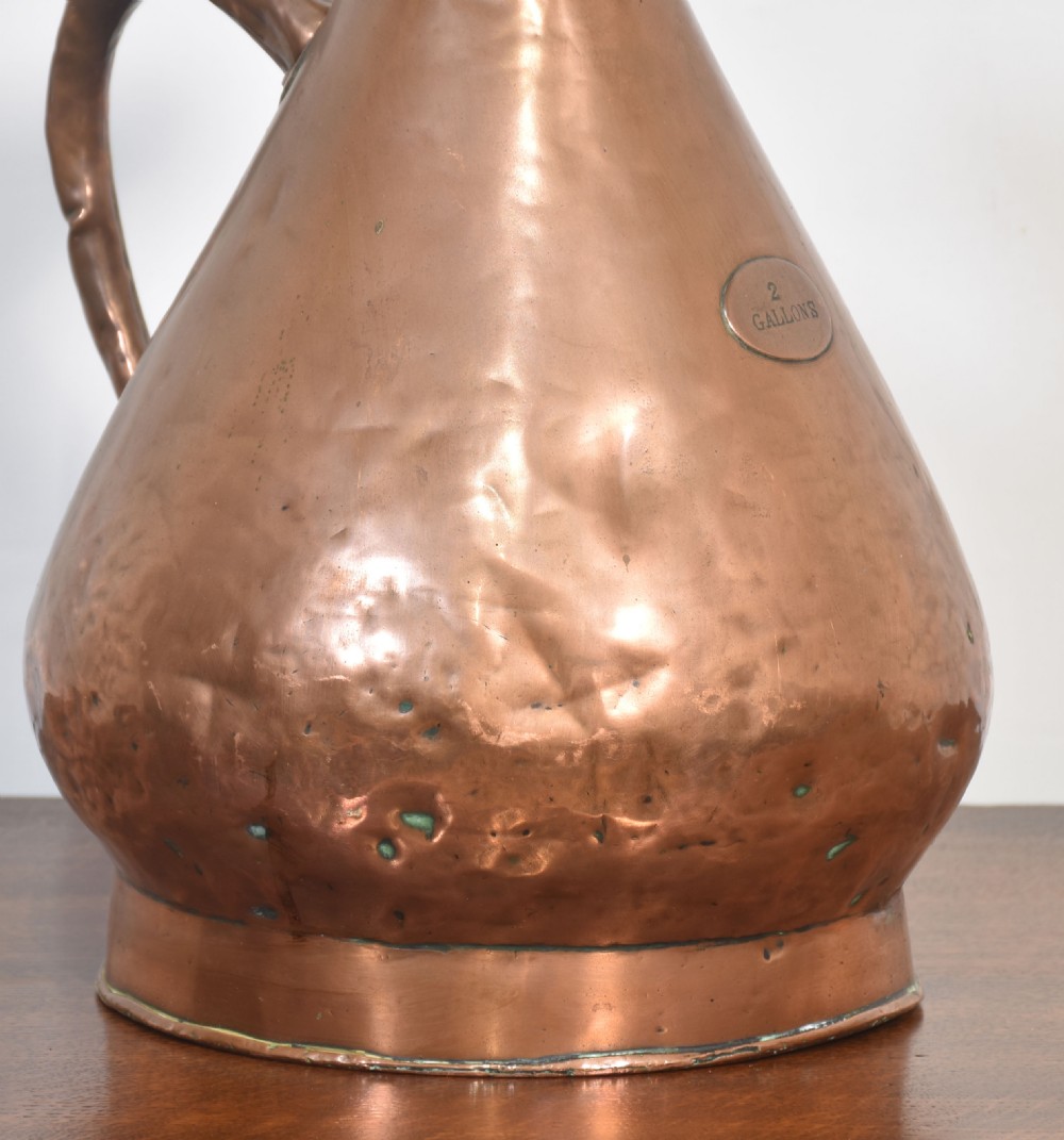 A nineteenth-century hammered copper haystack-shaped liquid measure with a riveted side handle and flared pouring lip. View VI