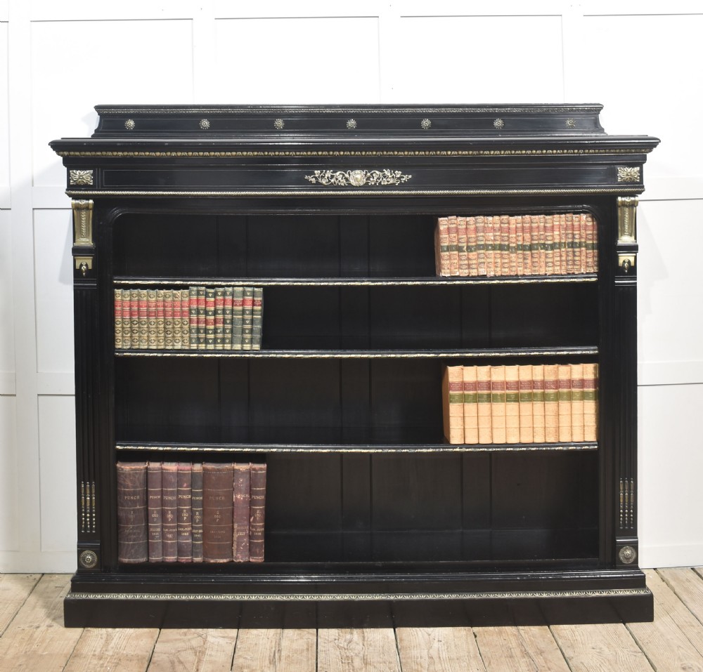 A large black ebonised open bookcase featuring four open shelves decorated with ornate brass mounts and a raised gallery top. View III