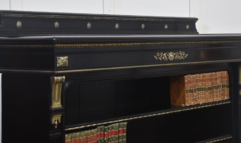 A large black ebonised open bookcase featuring four open shelves decorated with ornate brass mounts and a raised gallery top. View XI