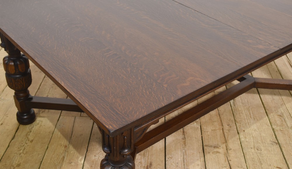 A dark oak extending dining table with carved bulbous legs and an H-stretcher base. View VII