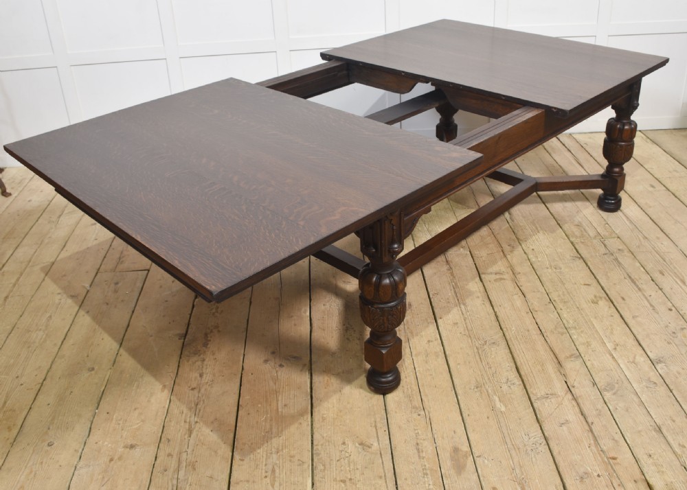 A dark oak extending dining table with carved bulbous legs and an H-stretcher base. View VIII