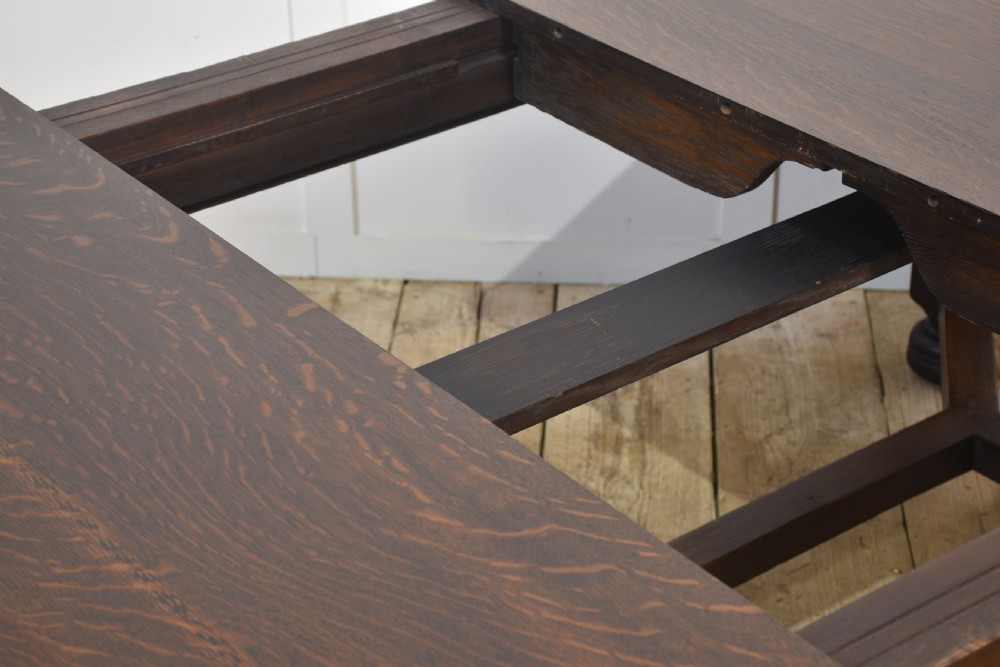 A dark oak extending dining table with carved bulbous legs and an H-stretcher base. View IX