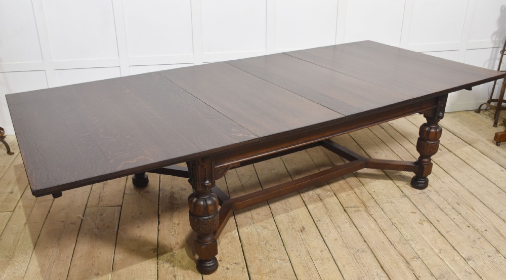 A dark oak extending dining table with carved bulbous legs and an H-stretcher base. View X