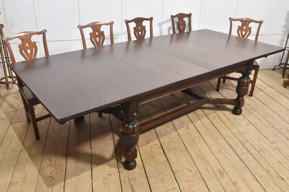 A dark oak extending dining table with carved bulbous legs and an H-stretcher base. View XII
